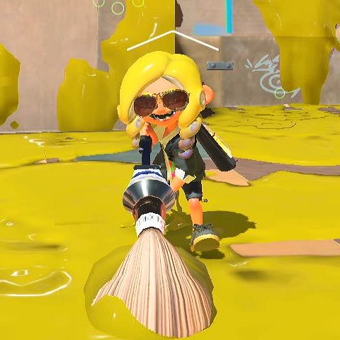 an octoling wielding a brush, painting the floor yellow while grinning into the camera