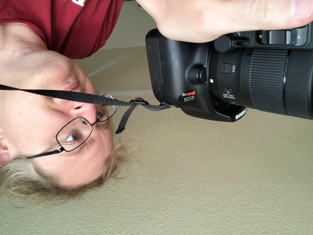I'm holding a camera several inches from my face, with an awkward strap