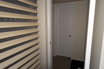 blinds, an open doorway, and a closed door; it's somewhat brighter than the previous image