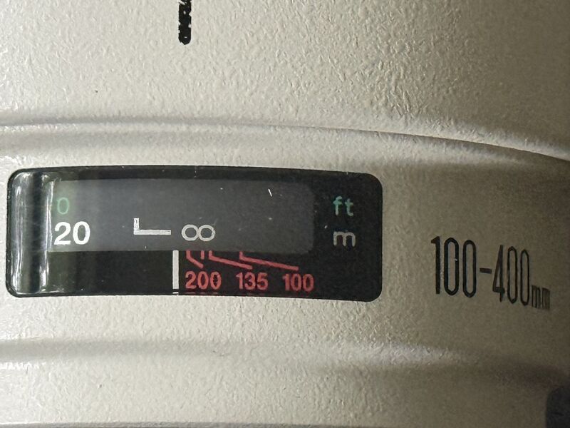 four red lines, three labeled 200, 135, and 100, on a white 100-400mm lens