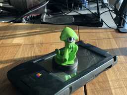 a green squid figurine on an apple newton